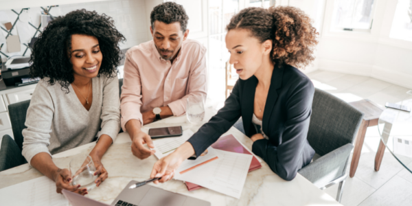 Financial Literacy Month - Female Advisor pointing to computer screen and talking with two clients