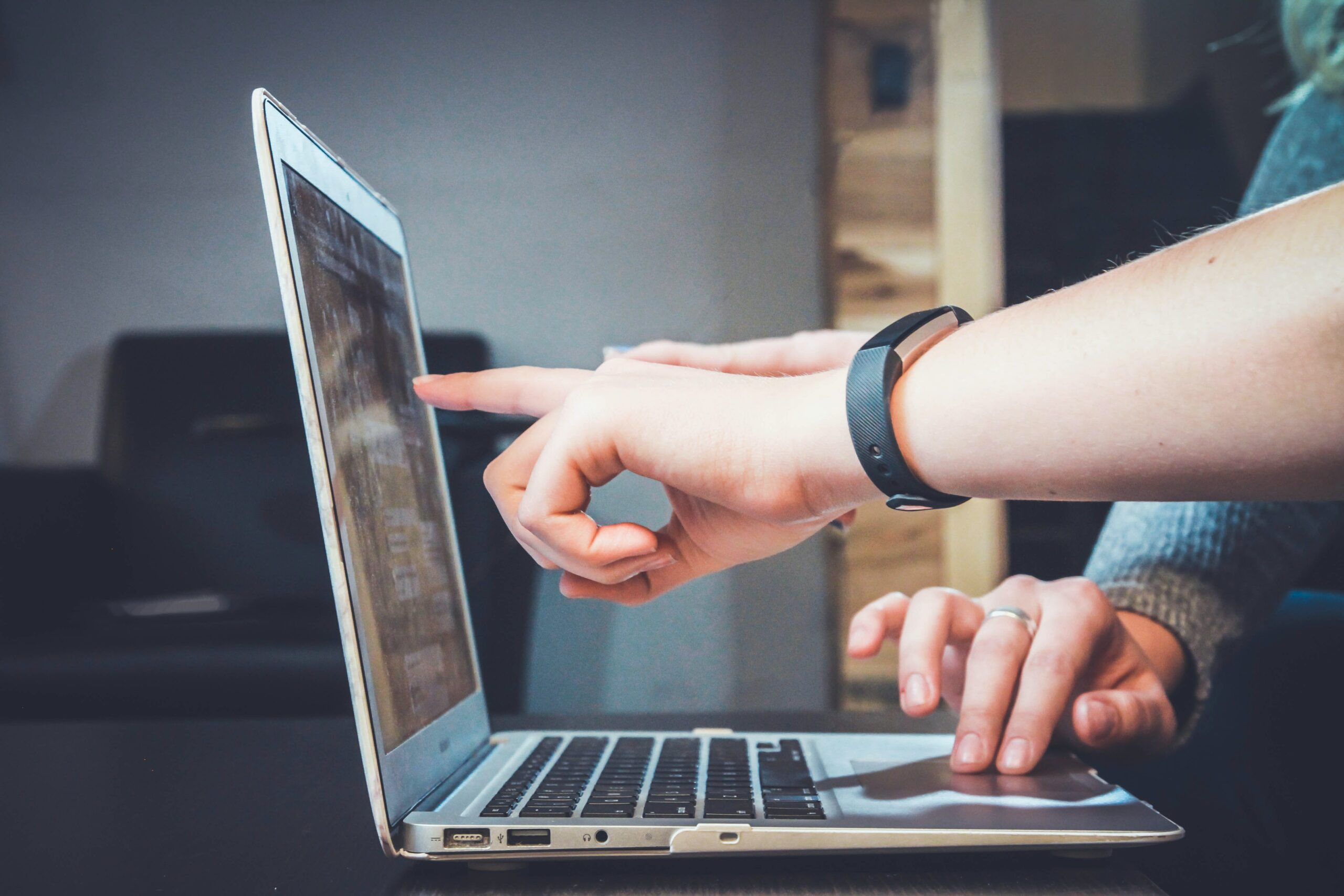 Hand pointing to computer screen in collaboration with colleague